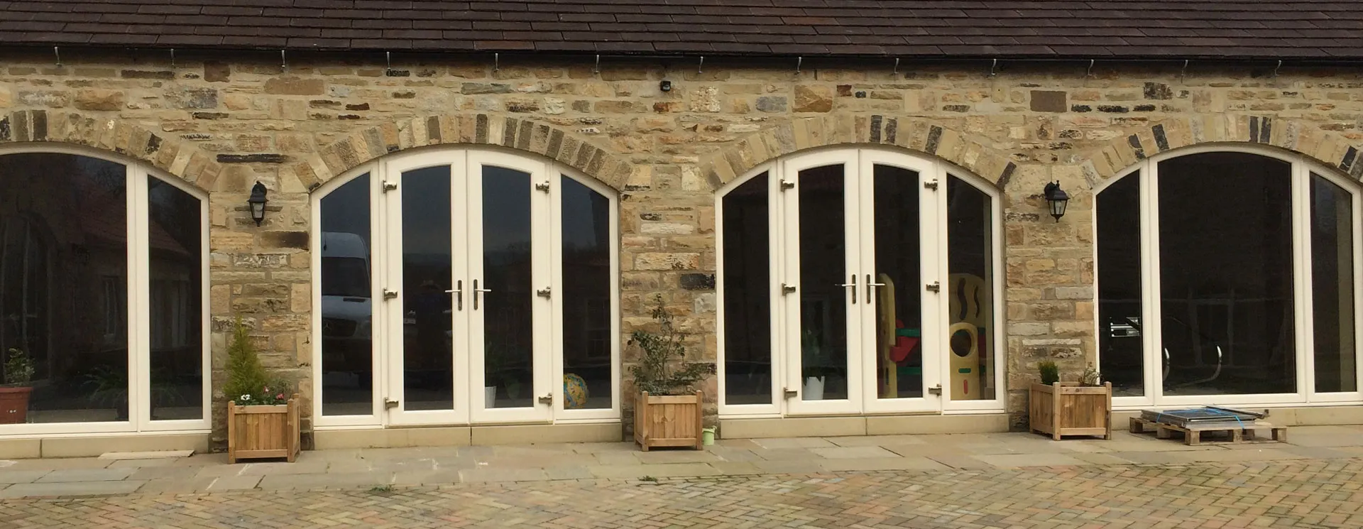 Stone barn conversion with four arched glazed openings, two of them white French doors
