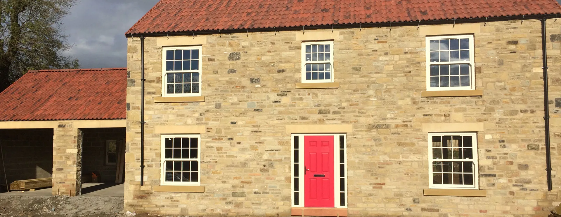 Stone house with white windows and a red front door