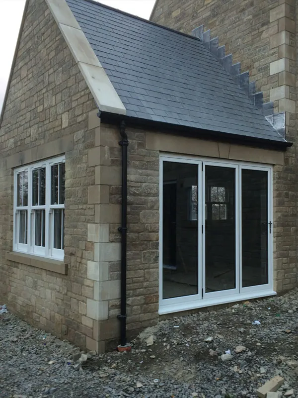 Stone extension with a white window and white glazed doors