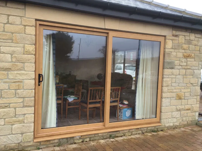 Oak woodgrain sliding patio door on a stone house