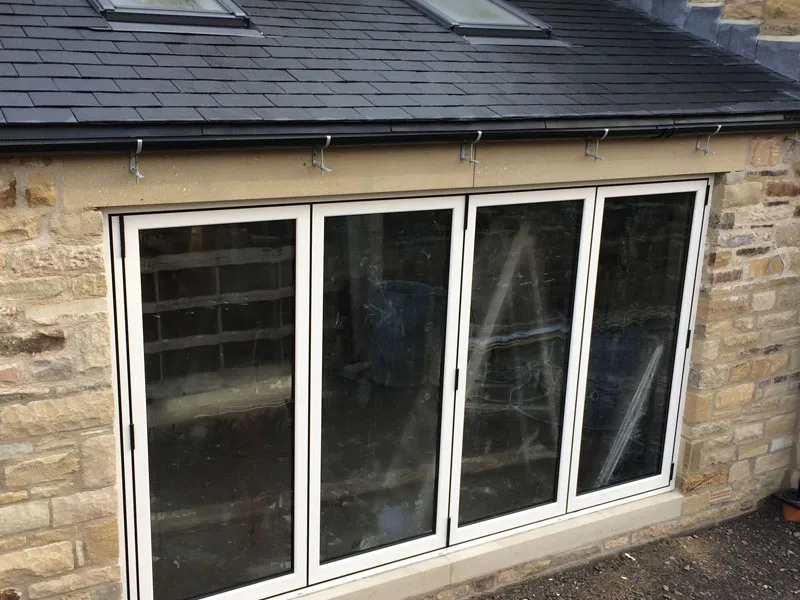 White bi-fold doors on a stone extension