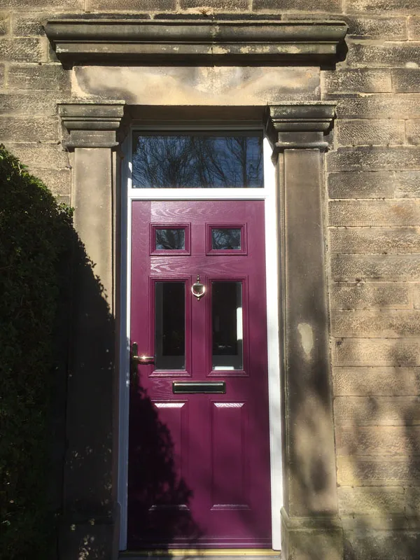 Plum composite front door in a stone surround