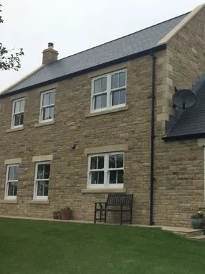 Stone house with white casement windows overlooking a lawn
