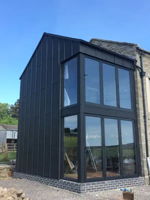 Two-storey dark clad extension with floor to ceiling corner glazing