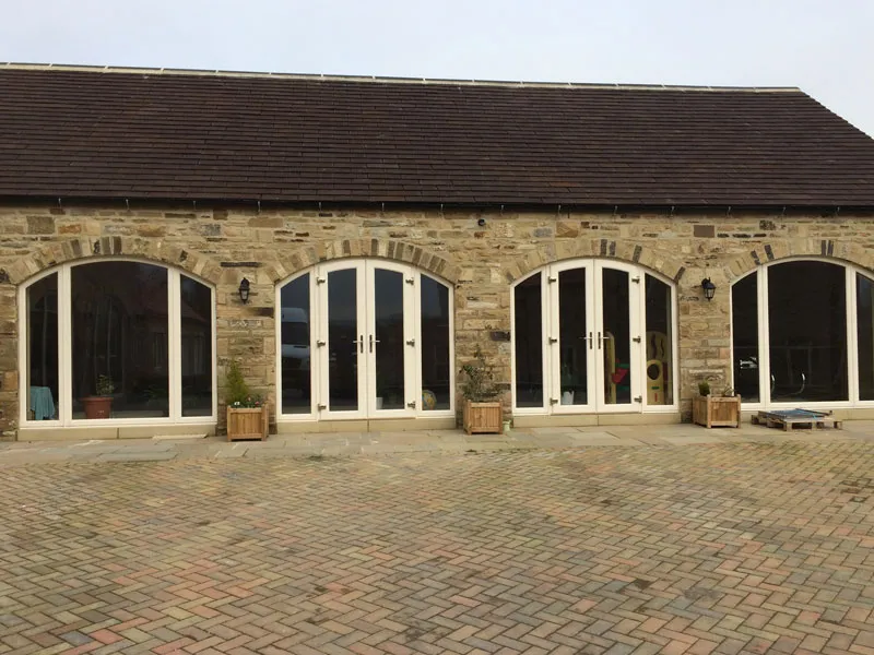 Stone barn conversion with arched French doors and windows