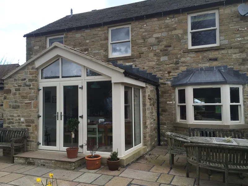 Gable-fronted conservatory and a bay window on a stone cottage