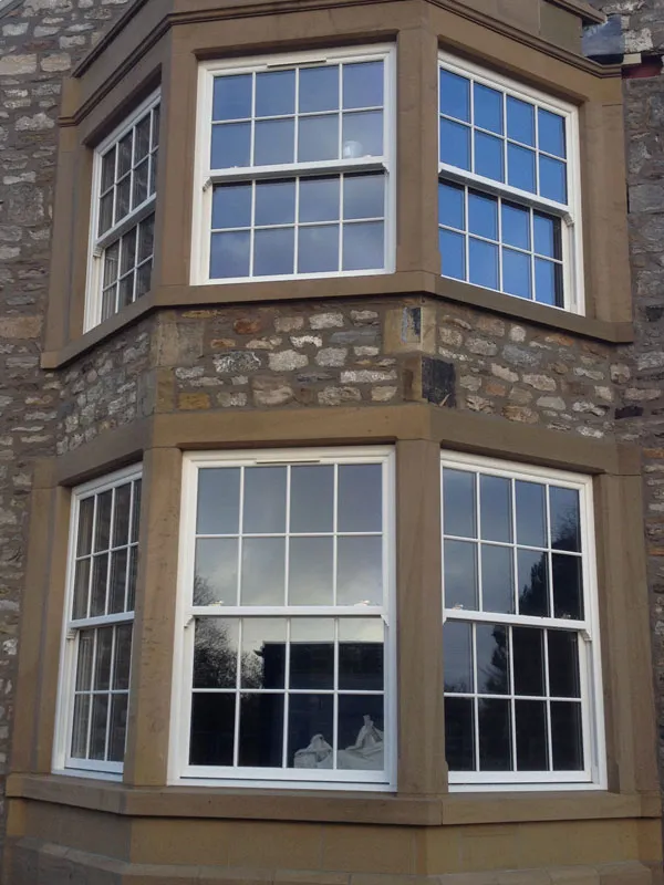 Two-storey stone bay with white sash-style windows