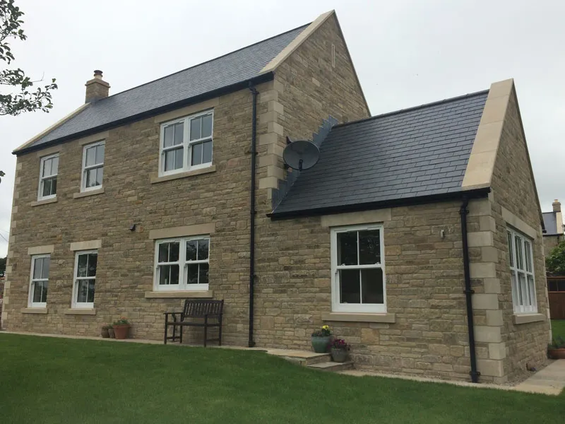 Stone house with white casement windows and a lawn